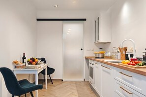Eine moderne Küche mit weißen Schränken, einer Holzausziehtafel und einem Essbereich mit Tisch und Stühlen.