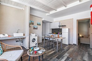 A compact kitchen with a dining area, a washing machine, and a small table with dishes.