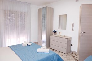 A hotel room with a bed, a dresser, a mirror, and a door.
