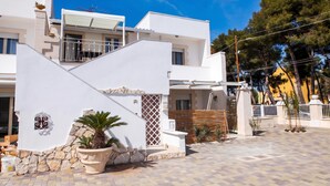 Un bâtiment moderne avec une façade en pierre, un balcon et une cour dallée.