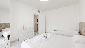 Una habitación de hotel moderna con una cama grande, una mesita de noche, un espejo y un armario.