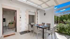 A dining area with a table set for four, surrounded by chairs, and a view of greenery outside. - Pino 6 - 2 bedrooms Near The Sea, Nardò, Italy (Nardò)