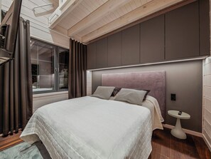 Un dormitorio moderno con una cama grande, una mesita de noche y una ventana con cortinas.