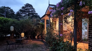 Une maison en briques avec un jardin, une table et des chaises.
