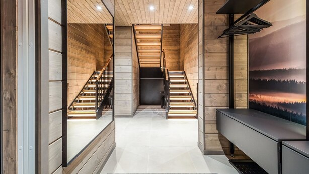 Un interior moderno con paneles de madera, una escalera central y un banco junto a la pared.