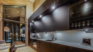 Una cocina moderna con armarios oscuros, un lavamanos de acero inoxidable y un microondas empotrado.