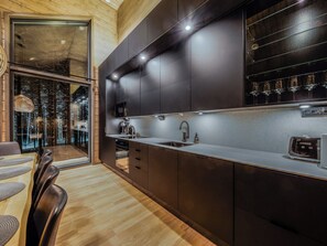 Une cuisine moderne avec des meubles de rangement aux couleurs sombres, un plan de travail en acier inoxydable et un meuble à vin intégré.
