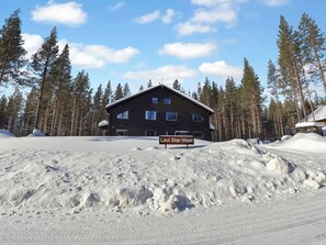 Un chalet à l’extérieur en bois sombre, doté de nombreuses fenêtres et d’une enseigne indiquant « Levi Star West ».