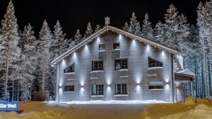 Un edificio de madera de varios pisos, con numerosas ventanas, rodeado de árboles cubiertos de nieve.