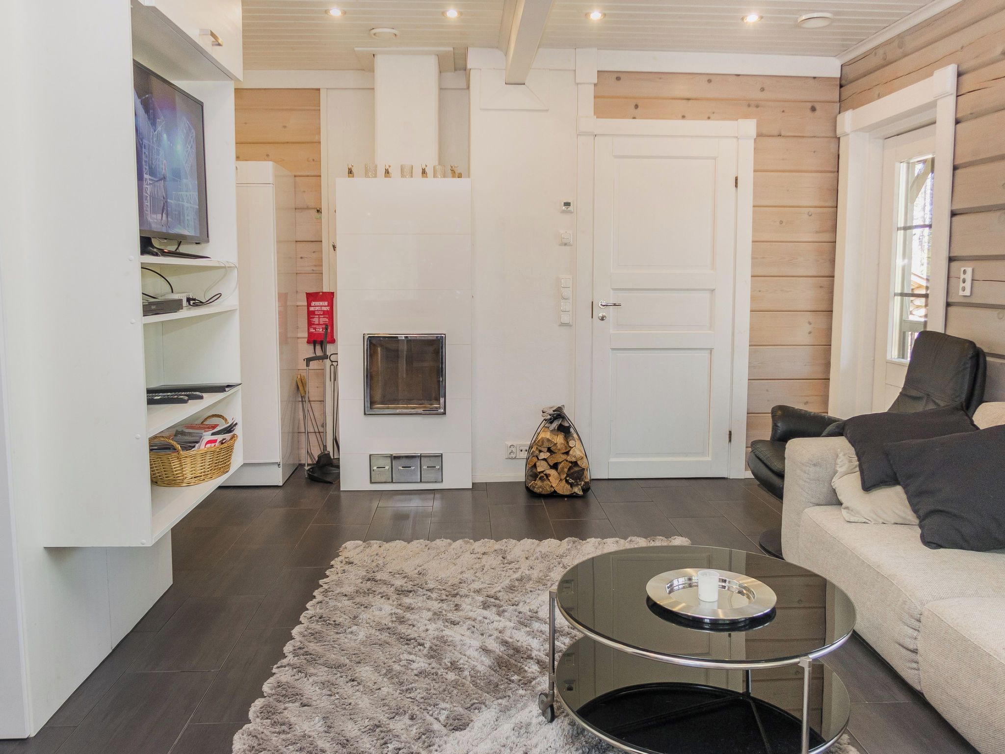 A modern living room with a fireplace, a sofa, a coffee table, and a television on a shelf.