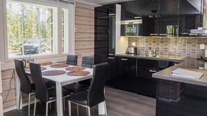 Une cuisine moderne avec un coin repas, dotée d’une grande fenêtre, de meubles de rangement noirs et d’un îlot central.