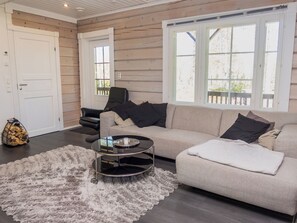 A living room with a beige sofa, a round coffee table, and a fluffy rug.