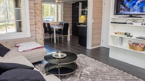 Un salon moderne avec un canapé, une table basse et un téléviseur posé sur une étagère blanche.