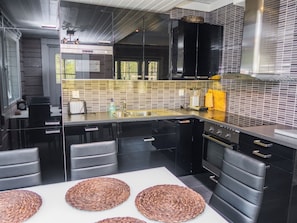 Eine moderne Küche mit schwarzen Schränken, einer Edelstahl-Spüle und einem eingebauten Backofen.
