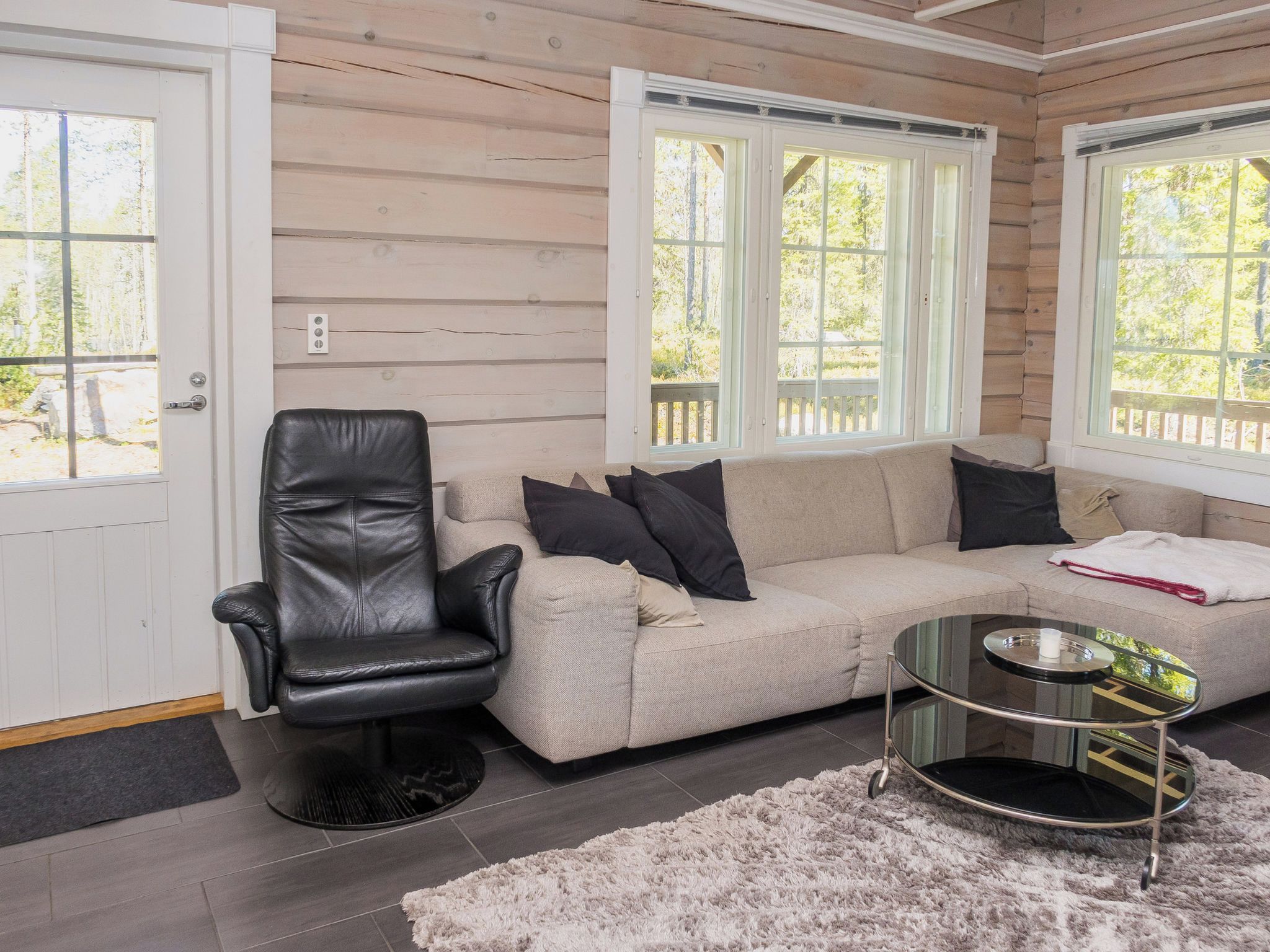 A cozy cabin interior with a leather chair, a sofa, and a glass coffee table.