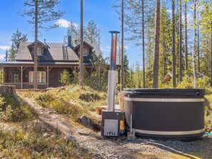 A cabin with a hot tub, surrounded by trees and a wooden deck. - Kiehtäjän kuohu by Interhome (Kuusamo)