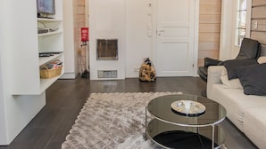 Un salon moderne avec une cheminée, un canapé, une table basse et un téléviseur fixé au mur.