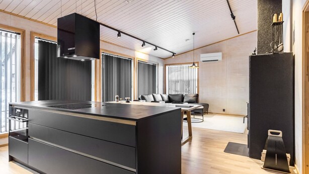 A modern kitchen with a large island, wooden flooring, and a dining area with a sofa and table. - Villa plywood by Interhome (Pudasjärvi)