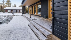 A modern log cabin with a wooden deck, large windows, and a snow-covered yard. - Villa plywood by Interhome (Pudasjärvi)