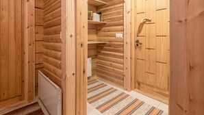A log cabin interior with wooden walls, a door, a radiator, and a striped rug. - Teknomaja by Interhome (Äkäslompolo)