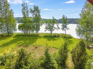Une zone herbeuse avec des arbres et un lac en arrière-plan.
