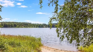 Näkymä järvelle, jossa on hiekkaranta, nurmialueita ja puita.