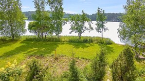 Ruohikkoalue, jossa on puita ja taustalla järvi.