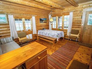A log cabin interior with a bed, seating area, and a television mounted on the wall.
