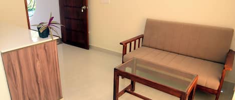 Una stanza con una scrivania in legno, un divano beige e un tavolino da caffè in vetro.