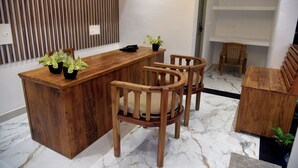 Un comptoir d’accueil en bois, avec deux chaises, une plante en pot et une petite table.
