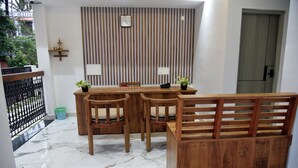Une table de salle à manger en bois, avec des chaises, un banc et une plante en pot.