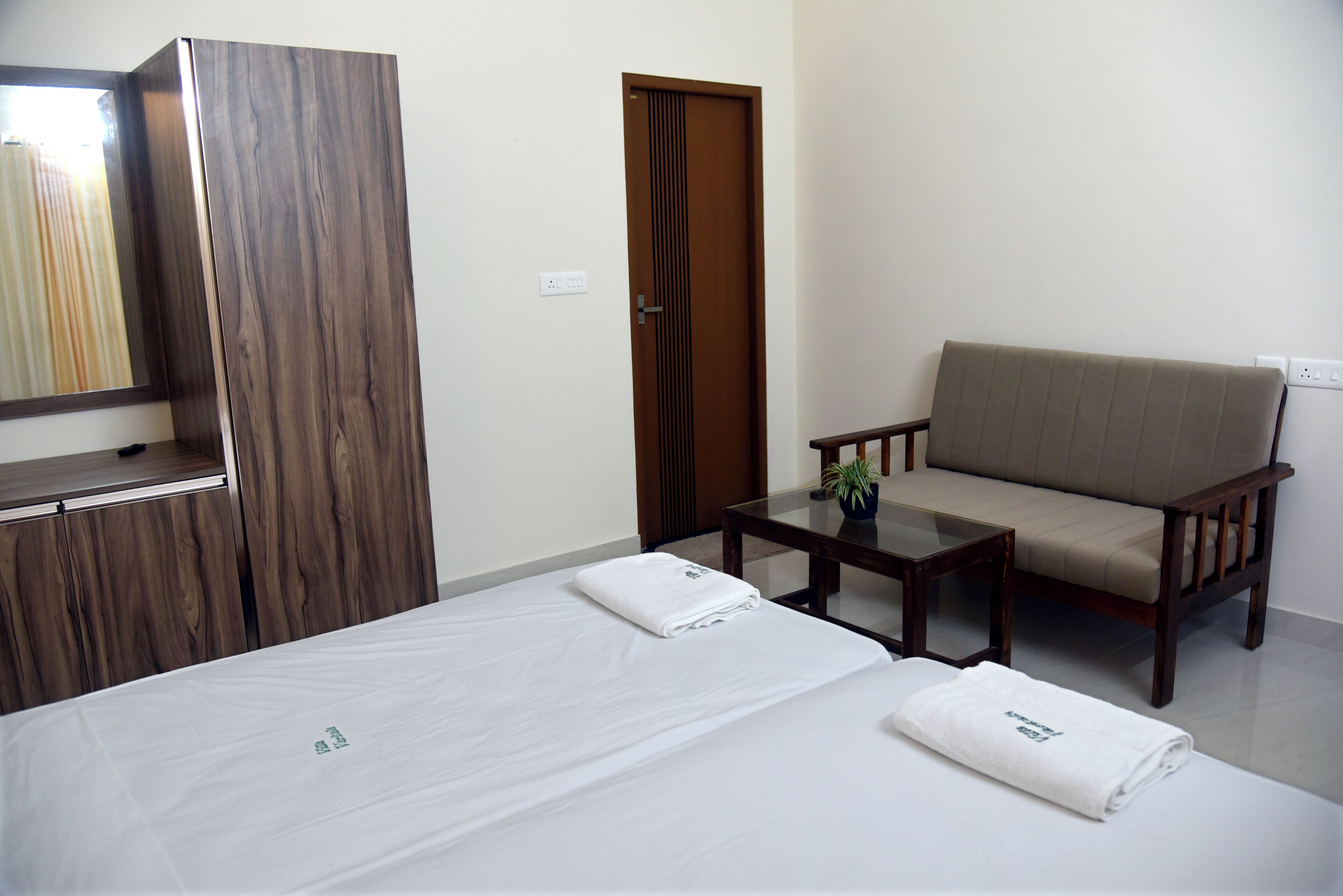 Una habitación de hotel con cama, sofá, una mesita, espejo y armario.