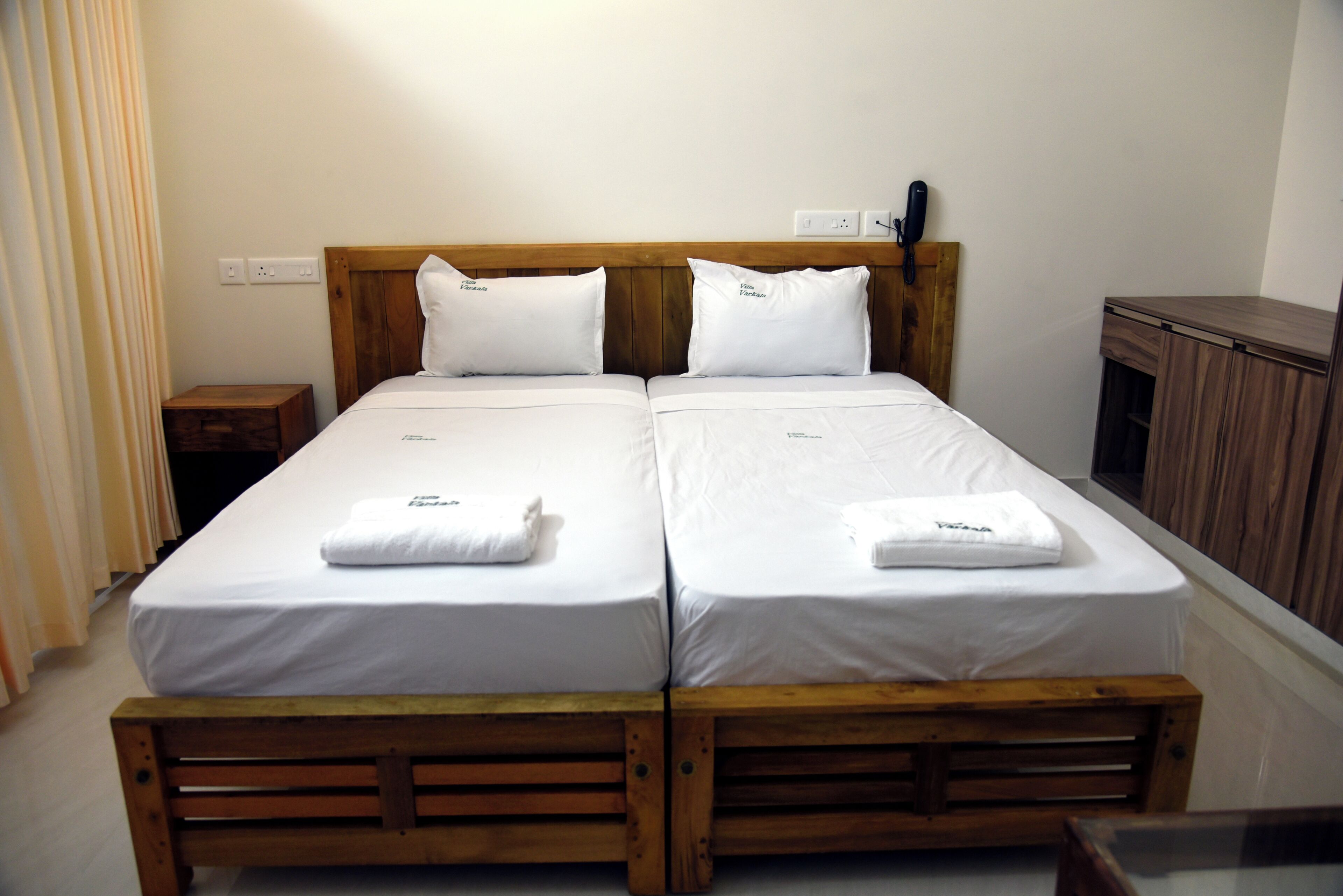 A double bed with two pillows, a wooden headboard, and a bedside table.