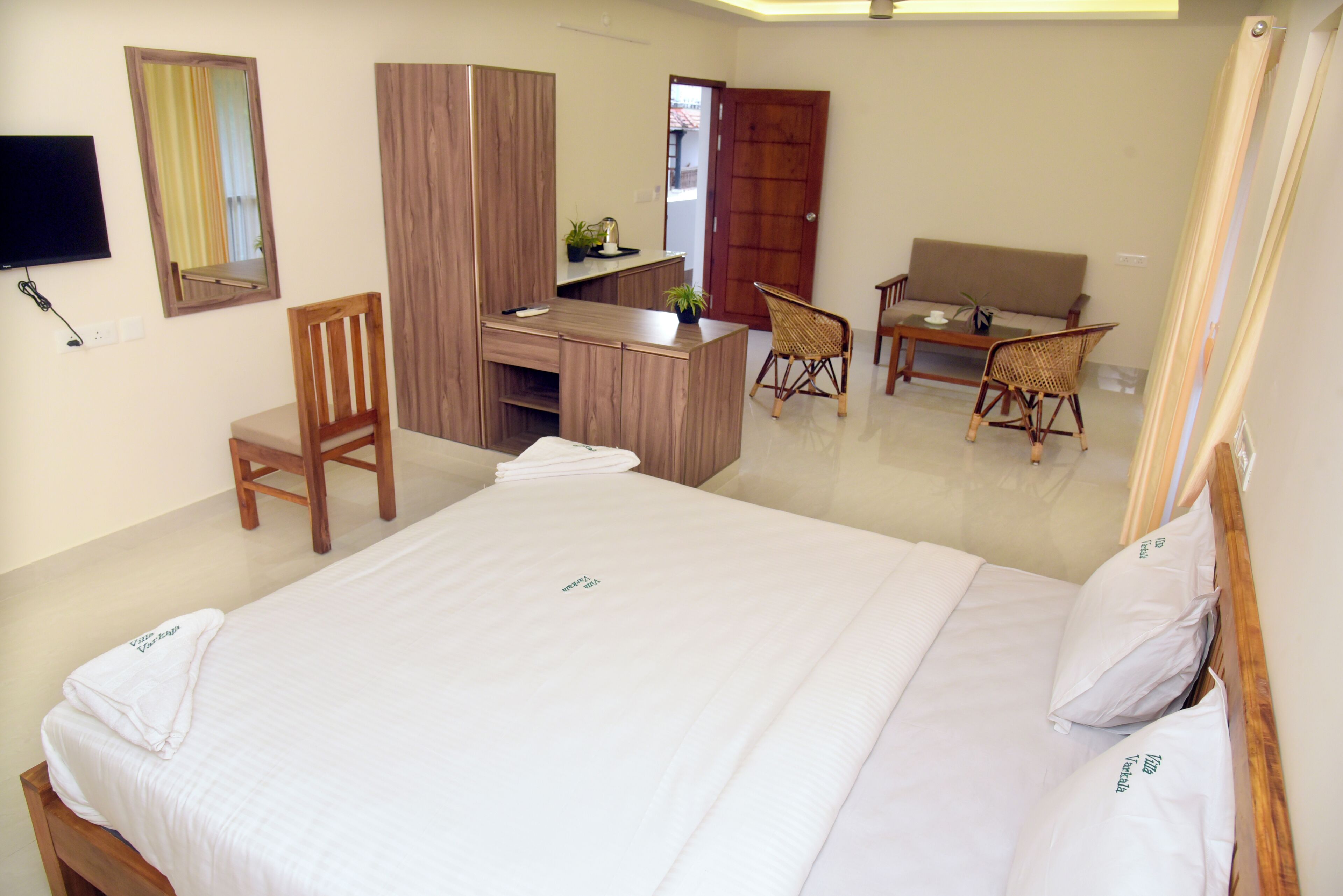 Una camera d'albergo con un letto, una scrivania, una sedia, un divano, una televisione e uno specchio.
