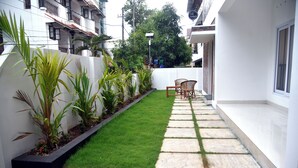 Un étroit sentier bordé d’une petite pelouse et d’une rangée de plantes en pot.