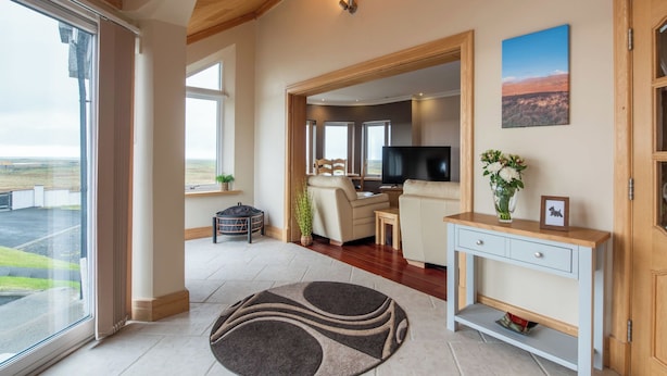 A spacious living area with a large window, a flat-screen TV, a sofa, a coffee table, and a console table with a vase and picture frame. - Benderloch House by Interhome (South Uist)