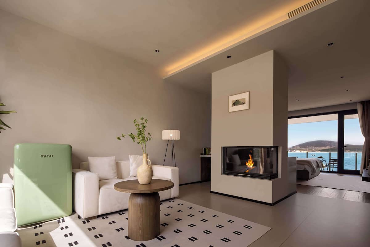 Una sala de estar moderna con un sofá, una mesa de centro, una chimenea y vistas al mar.