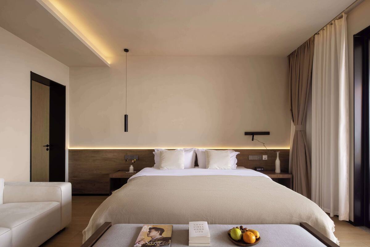 Habitación de hotel moderna con una cama grande, mesitas de noche y lámparas, y vistas al exterior.
