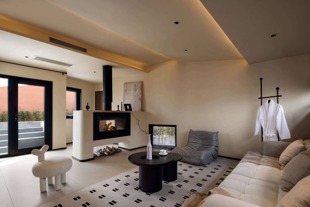 Una sala de estar moderna con chimenea, sofá y una silla blanca.