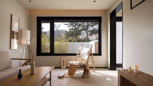 Una sala de estar moderna con un ventanal grande, un sofá, una mesa de centro de madera y un sillón.