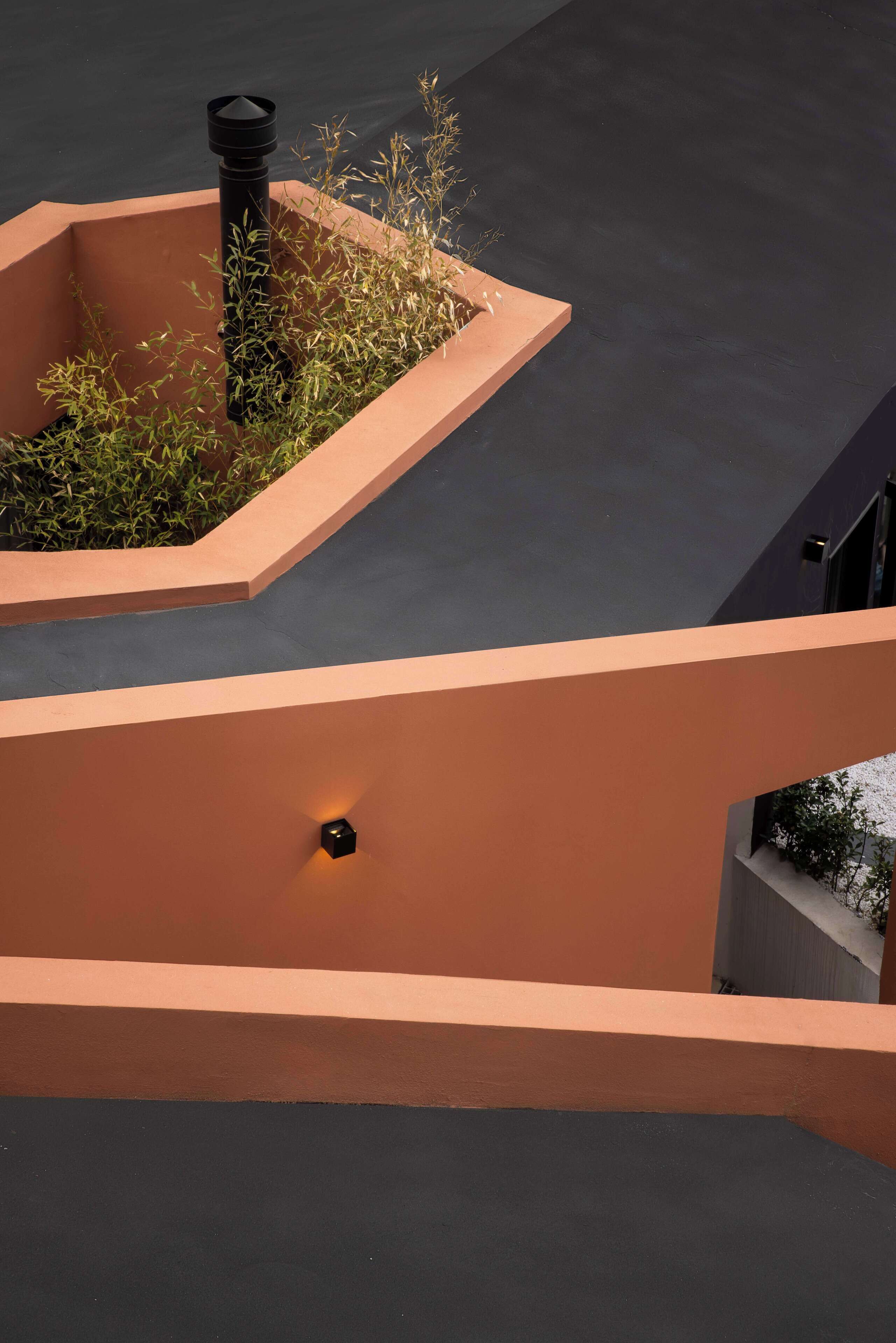 Terraço no telhado com um canteiro de plantas e uma estrutura preta.