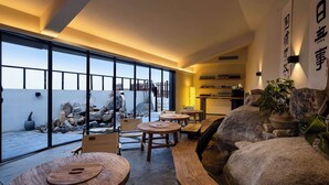 Un interior moderno con ventanas amplias, mobiliario de madera y una pared de piedra.