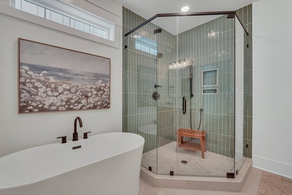 A modern bathroom with a freestanding bathtub, a glass-enclosed shower, and a wooden bench.