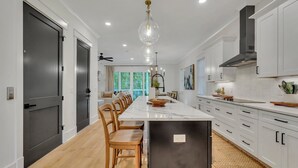 Una cocina moderna con una isla central, armarios blancos y un refrigerador negro.