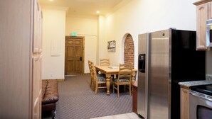 A compact kitchen with a refrigerator, stove, and dining table with chairs. - The Leadville Bunkhouse (Leadville)