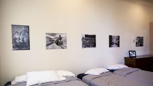 A bedroom with two beds, a dresser, and four black-and-white photographs on the wall. - The Leadville Bunkhouse (Leadville)
