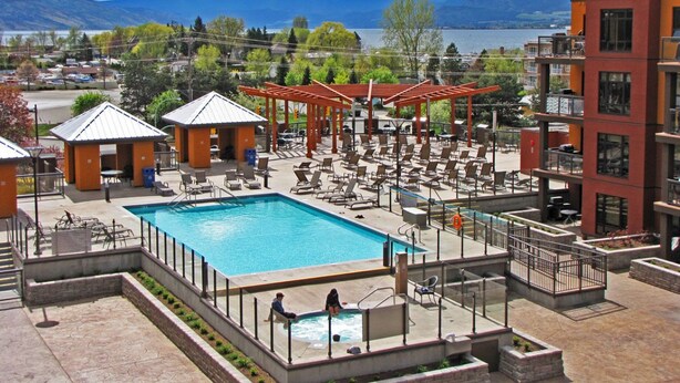 Un área de piscina en la azotea con múltiples sillones de descanso, una piscina y vistas a las montañas.