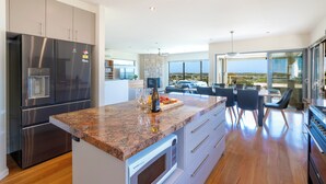 A modern kitchen with a granite countertop, stainless steel appliances, and a dining area with a view. - 94 Aldebaran Rd.  (Ocean Grove)