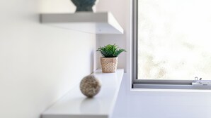 A minimalist room with a white shelf, a potted plant, and a decorative sphere. - 94 Aldebaran Rd.  (Ocean Grove)