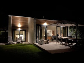 Una casa moderna con patio, area salotto all'aperto e tavolo da pranzo.